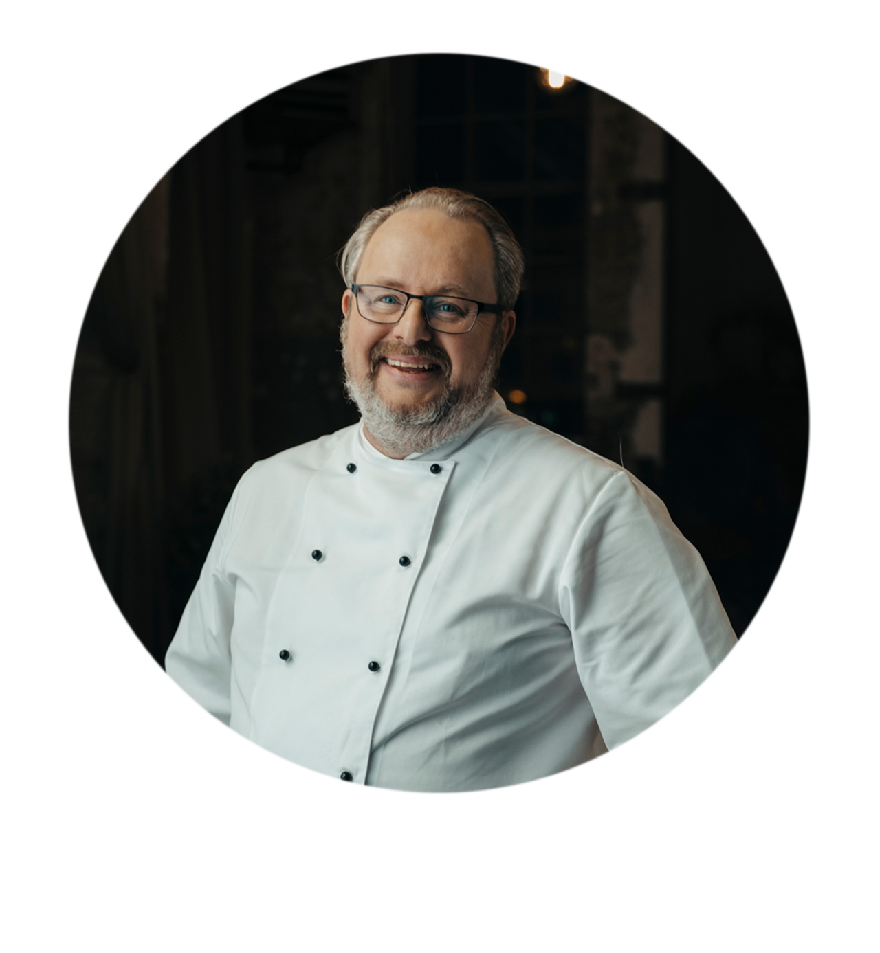 Bildporträtt av Joakim Lundblad med glasögon iklädd i klassisk kockoutfit